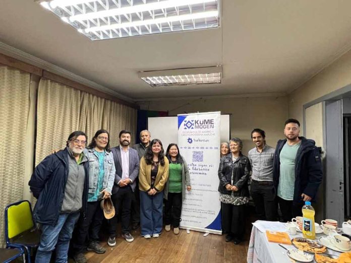 El Ministerio de Energía y la Agencia de Sostenibilidad Energética (AgenciaSE) anunciaron la adjudicación de los dos proyectos seleccionados en el concurso “Pilotos de Energía Cooperativa”, iniciativa que busca diseñar e implementar experiencias demostrativas de generación distribuida bajo un modelo asociativo y con gobernanza cooperativa. El concurso, financiado por el Ministerio de Energía, tiene como objetivo impulsar proyectos de generación solar fotovoltaica bajo la modalidad de Propiedad Conjunta, establecida en la Ley 21.118, permitiendo que un grupo de personas usuarias comparta la propiedad de un equipamiento de generación renovable y reciba los beneficios económicos de la energía inyectada a la red eléctrica, mediante descuentos en sus cuentas de electricidad. Proyecto Piloto en Temuco El proyecto adjudicado en la comuna de Temuco será implementado por la Cooperativa de Trabajo Kincha, con el patrocinio de la Cooperativa de Ahorro y Crédito Endógena Mapuche Küme Mogen, organización financiera indígena con 10 años de trayectoria y 943 socias y socios activos. La iniciativa contempla la instalación de un sistema fotovoltaico de 10 kWp en el techo de las oficinas de la cooperativa en Temuco. La planta tendrá una generación anual estimada de 11.140 kWh, permitiendo un ahorro anual proyectado de aproximadamente $1.400.000 y evitando la emisión de 67 tCO₂eq durante su vida útil. Las personas beneficiarias directas serán cinco socias y socios fundadores de la cooperativa Küme Mogen, quienes han sido priorizados bajo criterios internos de solidaridad, junto con el empalme eléctrico que abastece las oficinas de la propia cooperativa. Se estima un ahorro promedio anual de $192.000 por persona beneficiaria, junto con la constitución de un fondo colectivo para operación y mantenimiento. Küme Mogen es la primera cooperativa mapuche de ahorro y crédito del país, orientada al fortalecimiento del desarrollo económico y cultural del Wallmapu. Su misión se sustenta en el azmapu —ética propia mapuche— promoviendo el desarrollo endógeno, la reciprocidad (keyuwün) y el buen vivir (küme mogen). El proyecto energético surge como una estrategia para ampliar las herramientas de desarrollo económico frente al alza sostenida de las tarifas eléctricas y la creciente pobreza energética. Las personas beneficiarias indirectas incluyen al conjunto de los 943 socias y socios de la cooperativa y a las comunidades del Wallmapu donde esta tiene presencia, quienes podrán participar en instancias formativas y de difusión en energías renovables y gestión comunitaria. Más allá del impacto económico, el proyecto fortalece capacidades organizativas y técnicas con pertinencia cultural, proyectándose como el primer paso hacia la futura conformación de una cooperativa de energía. Proyecto Piloto en Macul En la comuna de Macul, el proyecto será ejecutado por la Cooperativa de Trabajo Red Genera, con el patrocinio de la Cooperativa Solar N°1 de Macul. La iniciativa contempla la instalación de una planta solar de 20 kWp en el techo del Gimnasio Municipal de Macul. La generación anual estimada es de 28.300 kWh, lo que se traduce en un beneficio económico anual cercano a $3.000.000. Las personas beneficiarias directas serán 22 familias vecinas de Macul y la Junta de Vecinos de Villa Santa Carolina, que representa a aproximadamente 1.200 viviendas. La energía inyectada será repartida en partes iguales (4,34% por persona usuaria), generando un descuento anual estimado de $130.000 por persona beneficiaria. Cada socio y socia aportará $20.000 anuales para cubrir los costos de operación y mantenimiento, totalizando un fondo de $500.000, gestionado por la cooperativa y rendido ante su asamblea. Un elemento central del proyecto es la colaboración de la Ilustre Municipalidad de Macul, que pone a disposición parte del techo del gimnasio municipal para el desarrollo de esta iniciativa cooperativa. Esta alianza público-comunitaria representa un hito en la promoción de la participación ciudadana en la transición energética, facilitando el uso de infraestructura pública para fines comunitarios y ambientales. Con este proyecto, Macul consolida una experiencia demostrativa de transición energética local, en la que municipio y ciudadanía cooperan para democratizar el acceso a la energía renovable y fortalecer el desarrollo territorial sostenible.